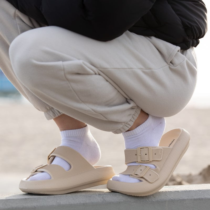 Women's tan sandals on concrete ledge